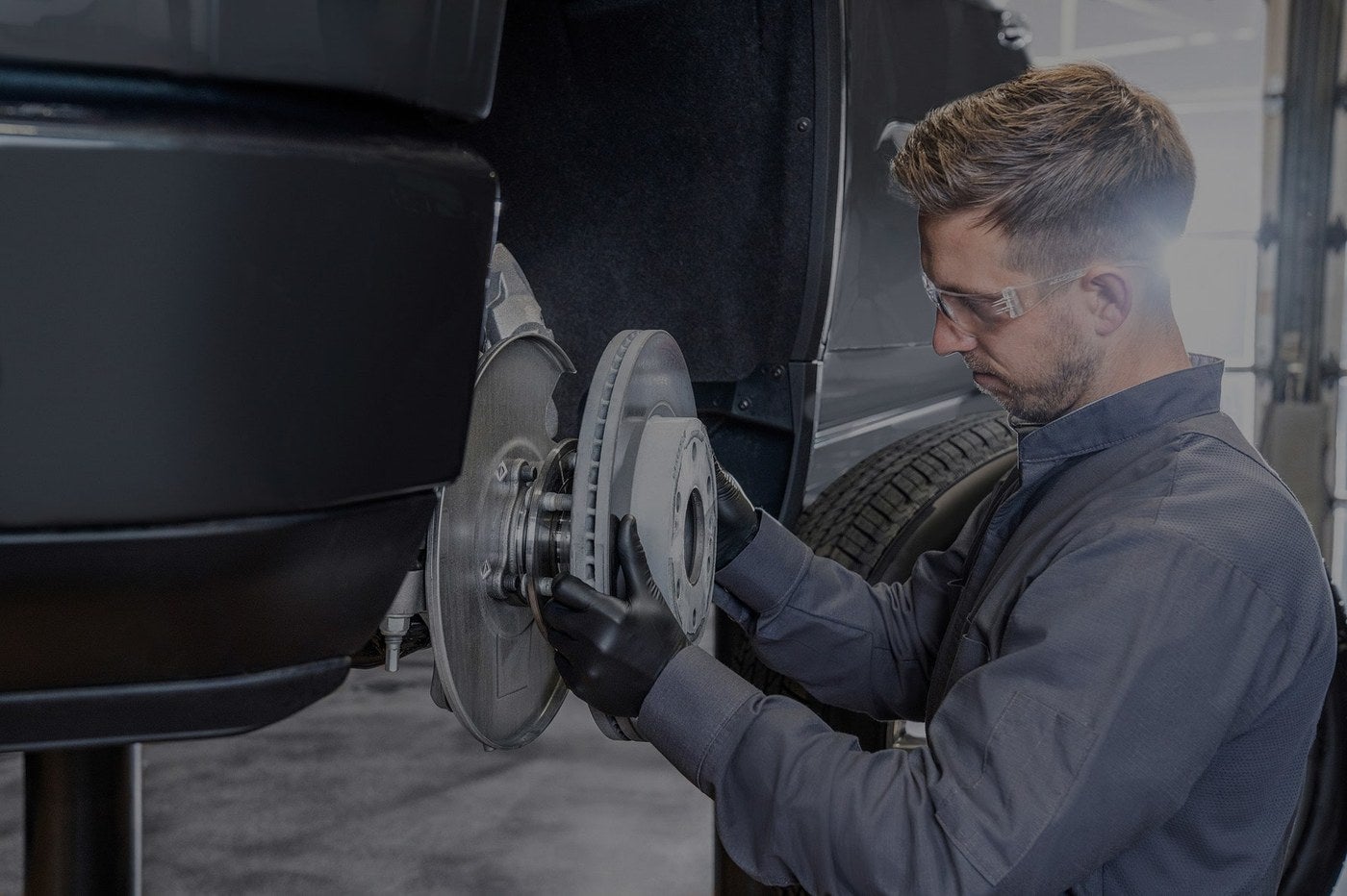GMC Certified Service technician replacing a brake rotor on a lifted vehicle in Graham, TX
