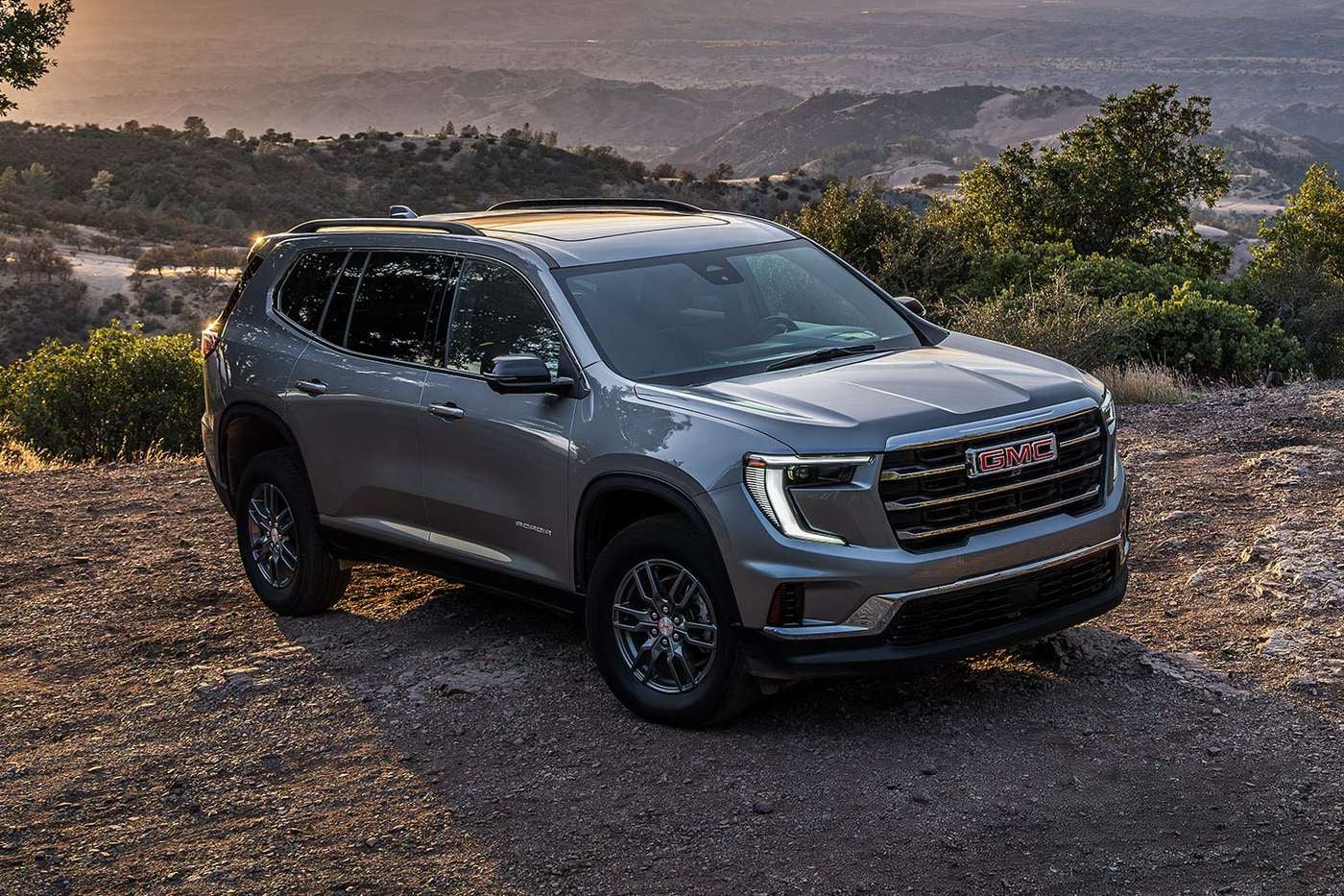 Gray GMC Acadia SUV parked on a hilltop at sunset, an example of a vehicle to inspect when buying used