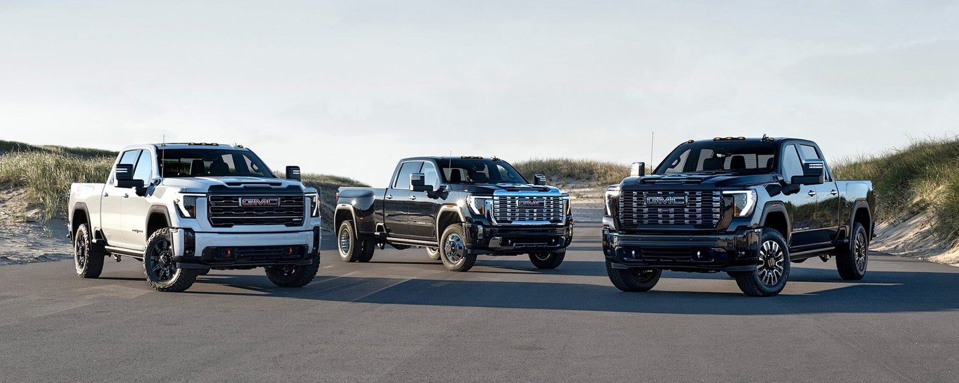 Three GMC Sierra HD work trucks parked side by side on a road